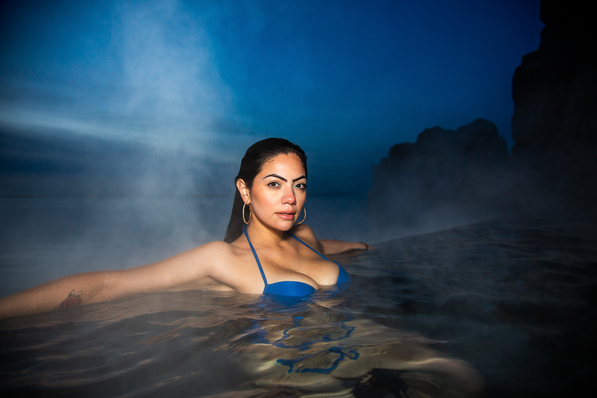 Woman in Sky Lagoon geothermal spa in Iceland surrounded by steam and volcanic landscape photographed by Ebis Hernandez