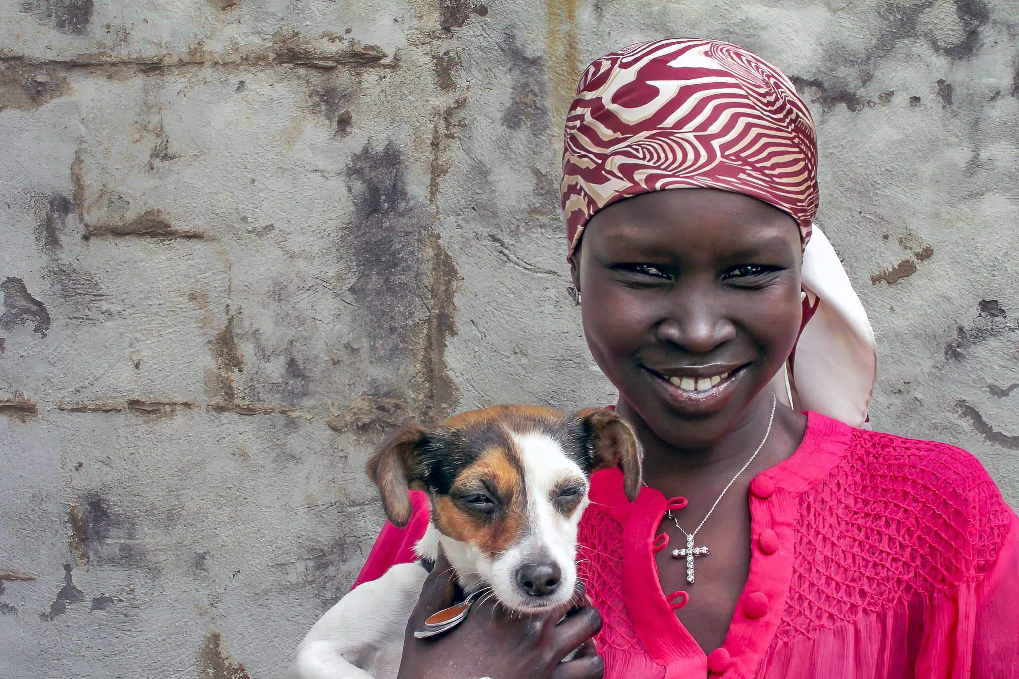 Alek Wek city portrait holding a dog in natural light against textured wall by photographer Ebis Hernandez