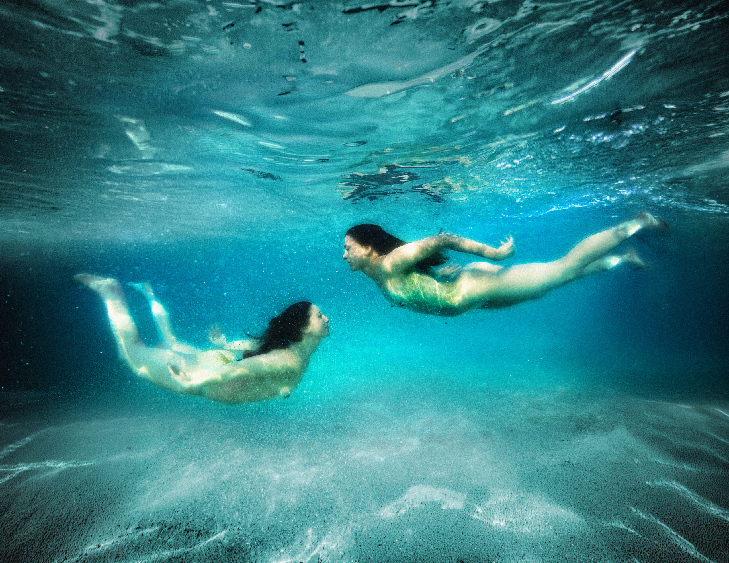 Two figures swimming underwater in a cinematic composition exploring movement and connection, part of the Beneath the Surface series by Ebis Hernandez