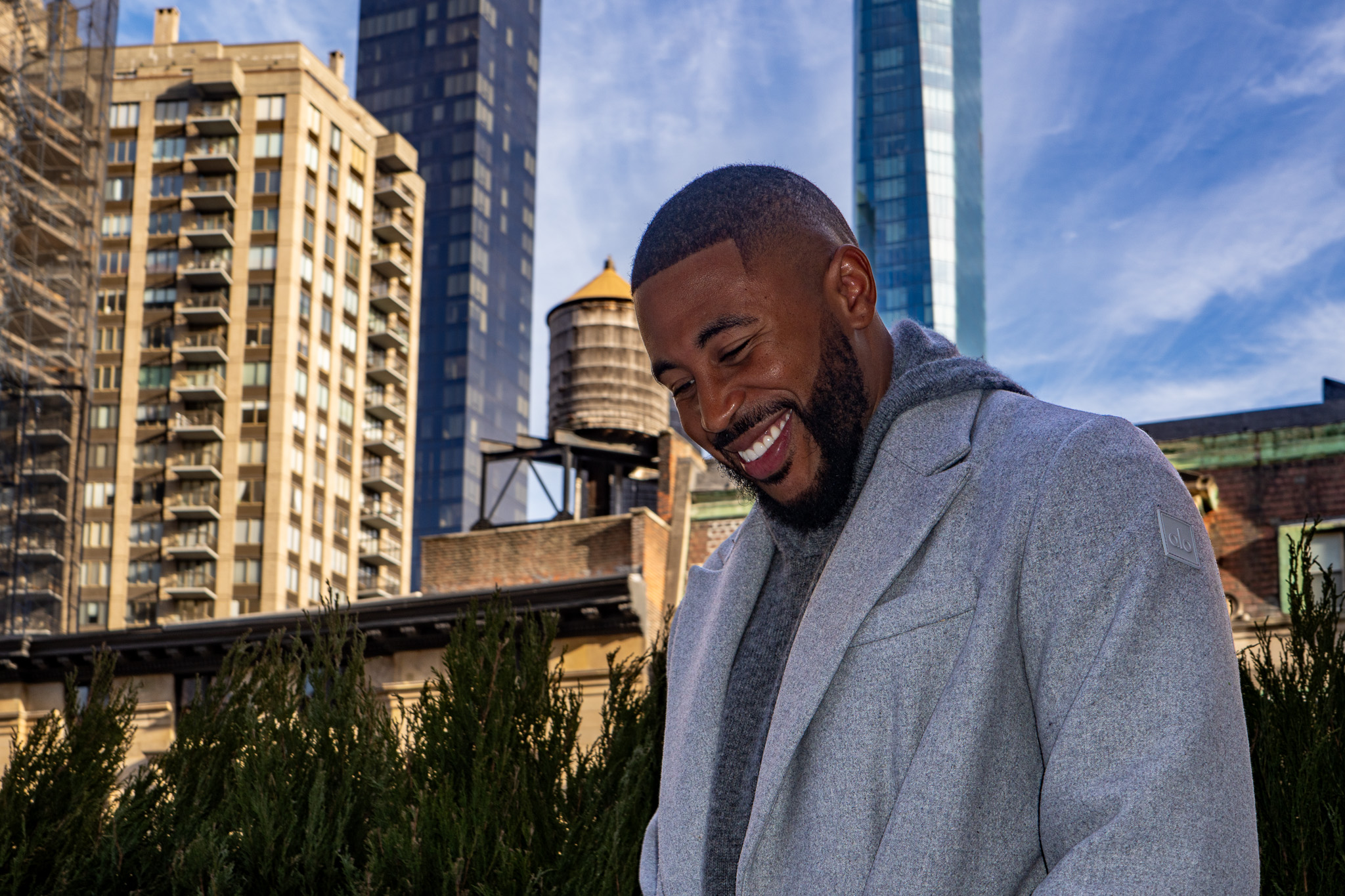 Blaise French smiling portrait at Secret Alo Gym in New York City with modern buildings behind him photographed by Ebis Hernandez