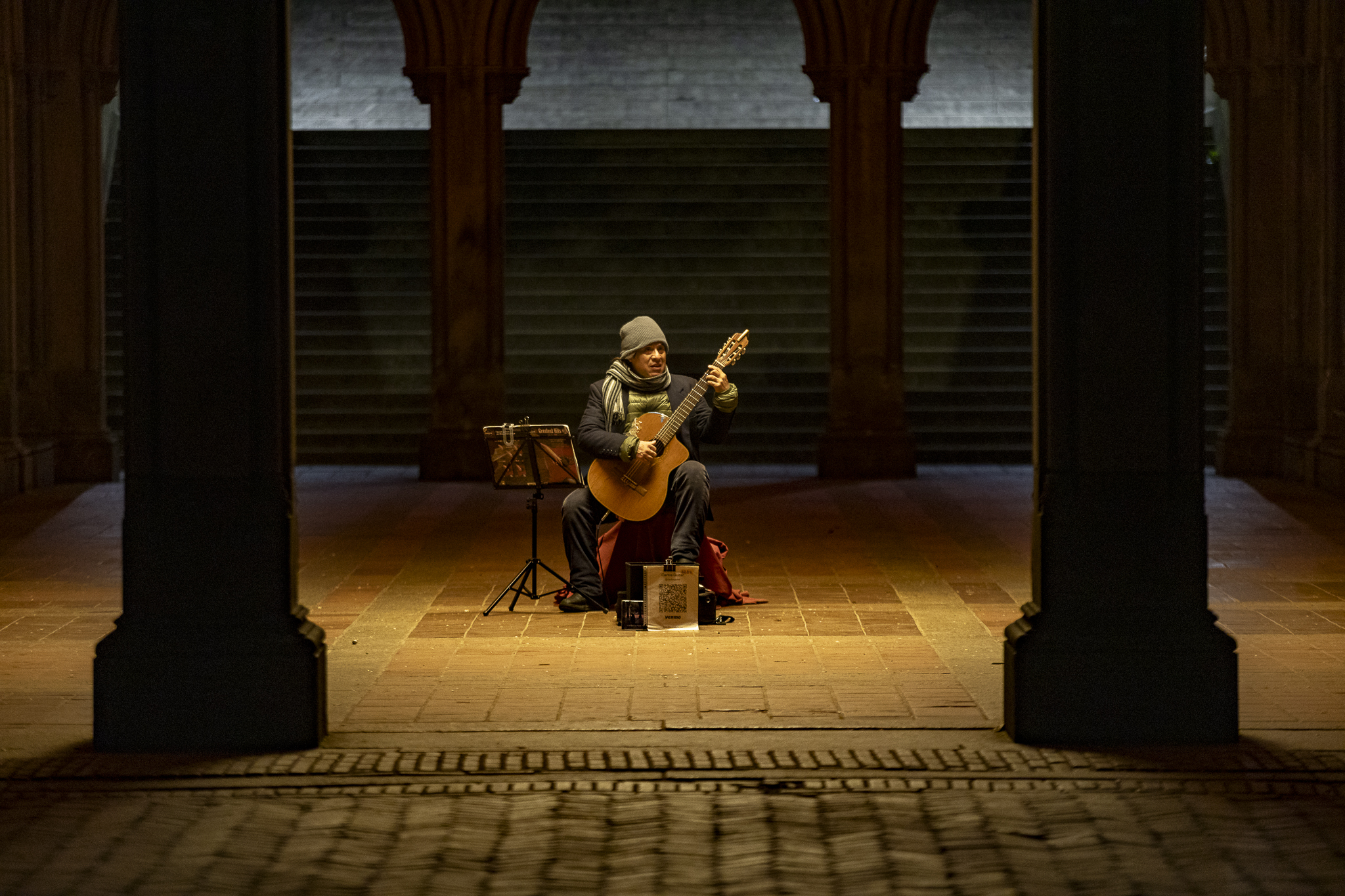 Guitarist performing at night under the arches of Bethesda Terrace.