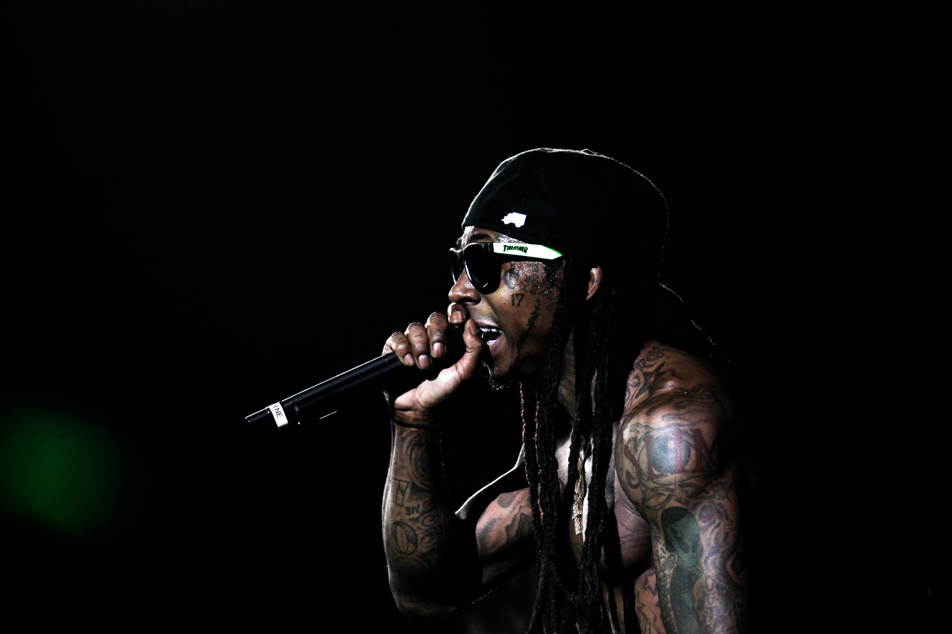 Lil Wayne performing live at Lil Weezyana Fest in New Orleans, holding a microphone on stage, photo by Ebis Hernandez