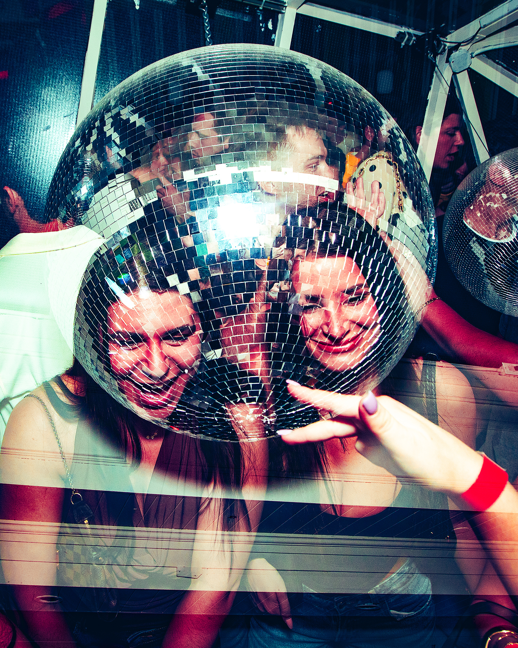 Close-up of faces reflected in a mirror ball with colorful lighting, photo by Ebis Hernandez